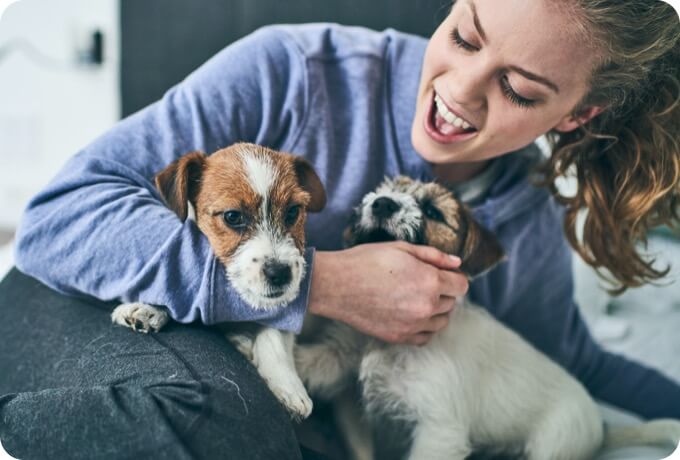 A woman plays with two puppies