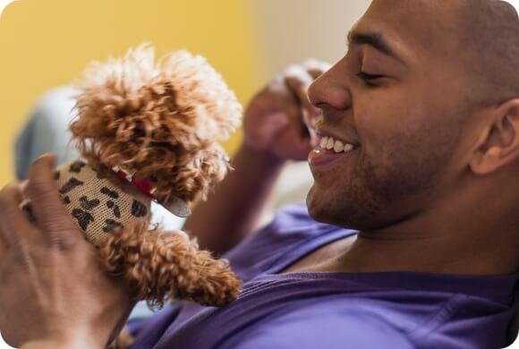 A very small puppy in a leopard-pattern sweater is held close to the face of its owner