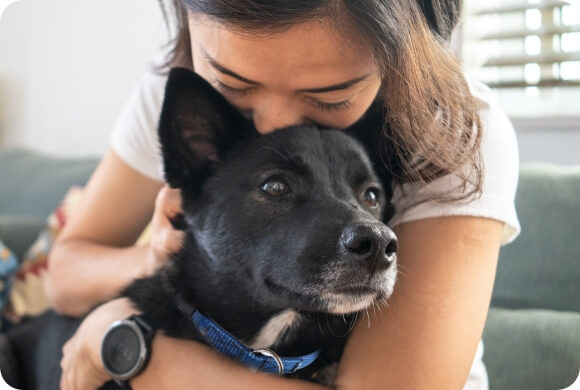 A woman kisses the top of her dog's head