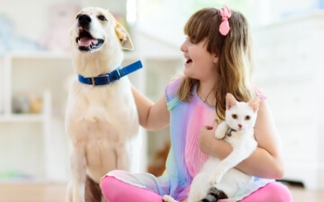 A happy girl pets her dog and her cat | Healthy Habits for New Pets